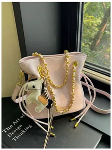 Detail of pink quilted bucket bag with gold chain strap and a small horse charm