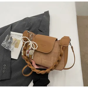Detail of vintage brown shoulder bag showing textured faux leather and plush charm