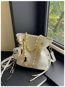 Detail of white quilted bucket bag with gold chain strap and cute horse charm