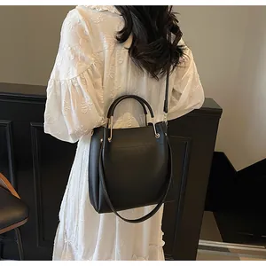 Vista posteriore della modella con borsa a secchiello nera su abito bianco ricamato