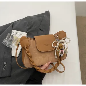 Detail of vintage square crossbody bag with woven strap and decorative pearl horse charm