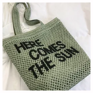 Detail of green woven tote bag with Here Comes The Sun embroidery on cotton mesh fabric