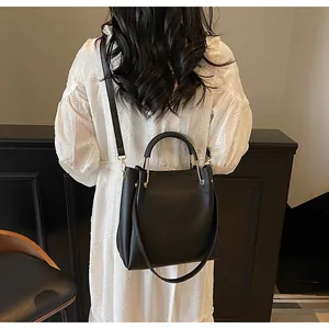 Dettaglio borsa a secchiello nera minimalista in pelle opaca con hardware dorato