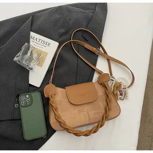 Detailed view of camel crossbody bag with woven handle and cute pony charm accessory