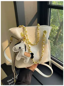 Close-up of quilted white bucket bag with gold chain and white pony charm detail
