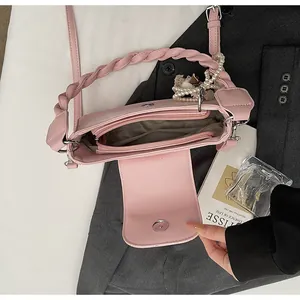 Pink crossbody bag detail showing interior compartments and woven handle with pearl charm