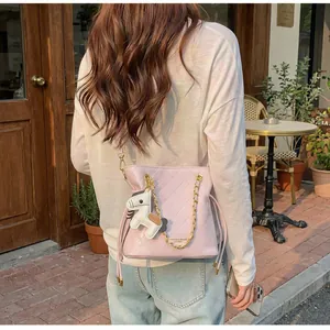 Detail view of pink quilted bucket bag with gold chain and pony charm accessory