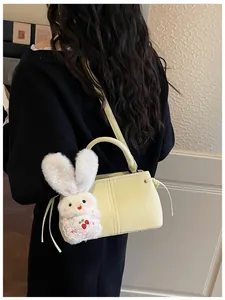 Close-up of soft yellow PU leather square bag with cute white bunny charm accessory