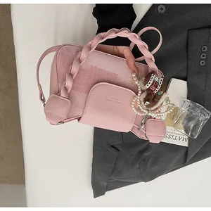 Pink velvet handbag detail with woven handle, pearl chain and decorative horse pendant