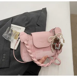 Detailed view of pink leather bag with woven strap, lace pony charm, and pearl pendant