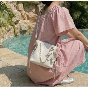 Close-up of white quilted bucket bag with gold chain strap and horse charm detail