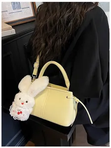 Detail of soft yellow PU leather crossbody bag with a cute plush bunny charm