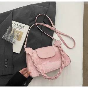 Detail of pink vintage crossbody bag featuring textured flap and woven handle design