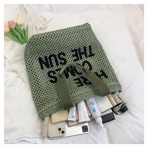 Detail view of large green woven beach tote bag with light green mesh and canvas handles