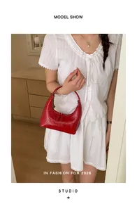 Detailaufnahme der roten glänzenden Hobo-Tasche mit Doppelreißverschluss am Model