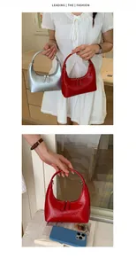 Detail der Halbmond-Tasche aus metallischem Silberleder und rotem Lackleder