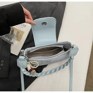 Detail view of light blue crossbody bag interior with woven handle and pearl charm