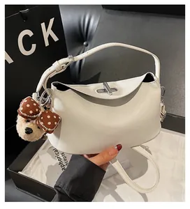 Detailansicht der cremefarbenen Ledertasche mit verstellbarem Griff und Bärenanhänger