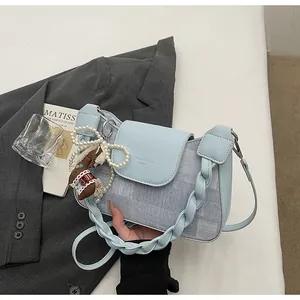 Detail of light blue woven crossbody bag with pearl bow and bear charm accessories