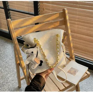Macro detail of white quilted bucket bag with gold chain strap and horse charm detail