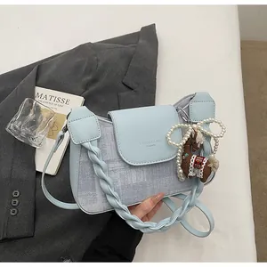 Detail of light blue crossbody bag with woven handle and elegant pearl chain accessory