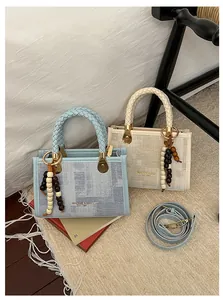 Vue détaillée des sacs carrés en tissu texturé avec poignées tressées et breloques décoratives