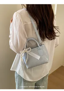 Dettaglio borsa a secchiello azzurra con fiocco di perle decorativo e nastro di raso