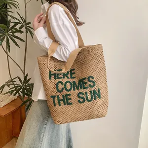 Large beige woven beach tote with green Here Comes The Sun embroidery shown on model