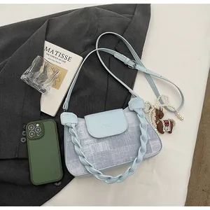 Detailed view of light blue denim shoulder bag with pearl and horse charms
