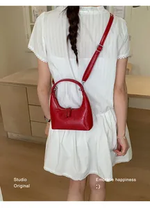 Detail der roten Mondsichel-Tasche aus Lackleder mit verstellbarem Riemen