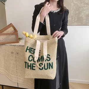 Cream woven beach tote bag with green 'HERE COMES THE SUN' text for summer travel
