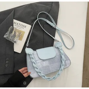 Detail of light blue crossbody bag featuring a unique braided handle and fabric texture