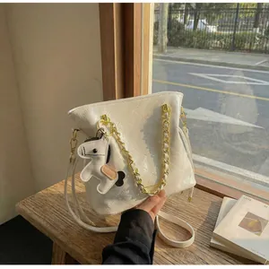 Close-up of beige quilted bucket bag with gold chain handle and horse charm on wood table