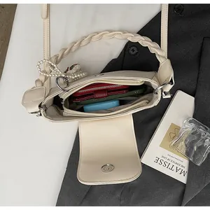 Interior view of off-white crossbody bag showing space for wallet, phone, and cosmetics