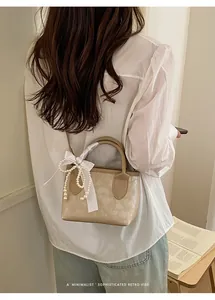 Dettaglio borsa tote retrò beige con elegante fiocco in raso e tracolla di perle