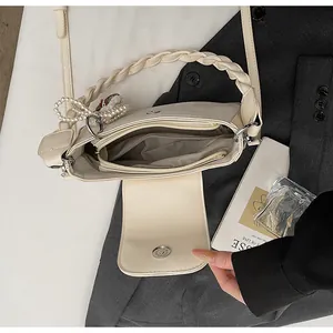 Detail view of the cream square bag interior with magnetic clasp and pearl charm