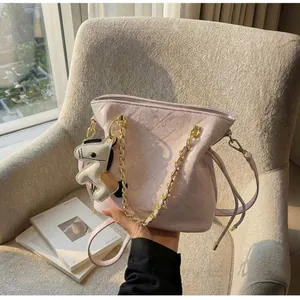 Detail of pink quilted bucket bag with gold chain and a small horse charm on a chair