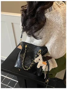 Detail of black quilted leather bucket bag with gold chain and pony charm accessory