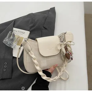 Detail of off-white crossbody bag with brand lettering, woven handle and charm on blazer