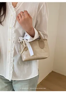 Dettaglio borsa retrò crema con perle e fiocco di seta mostrato su modella con camicia