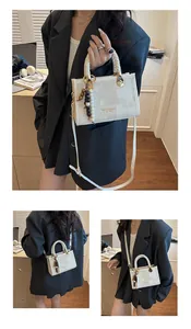 Détail du sac jacquard beige avec poignée tissée, finitions dorées et pompon décor