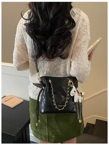 Detailed view of a black quilted bucket bag with golden chain and white pony charm accessory