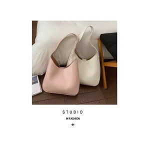Detail of minimalist hobo bags in pink and cream with refined stitching and wide straps