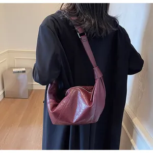Dettaglio della borsa a mezzaluna rosso vino con trama in PU plissettata e tracolla regolabile