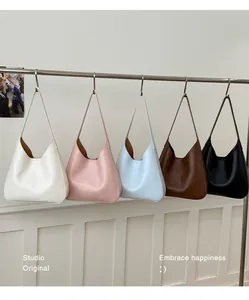 Detailed row of minimalist leather bucket bags in five colors on a studio hanger