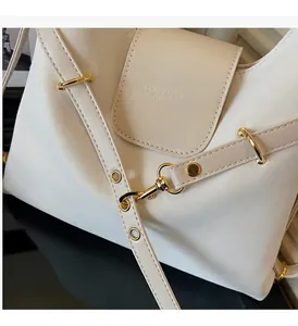 Detail van glanzende gouden hardware en gebroken wit leer op een luxe tote bag