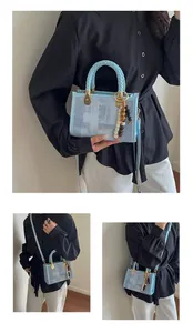 Détail du sac cabas en denim bleu clair avec poignées tressées et breloque en perles