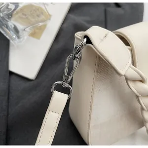 Detail of cream white leather bag with silver metal swivel clasp and woven decorative texture