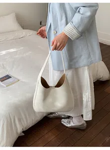 Close-up of cream leather bucket bag with brown lining worn with a blue blazer