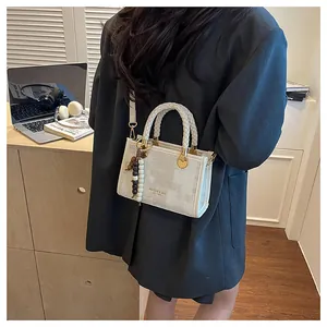 Détail d'un sac à main en toile beige avec poignée tissée et perles décoratives